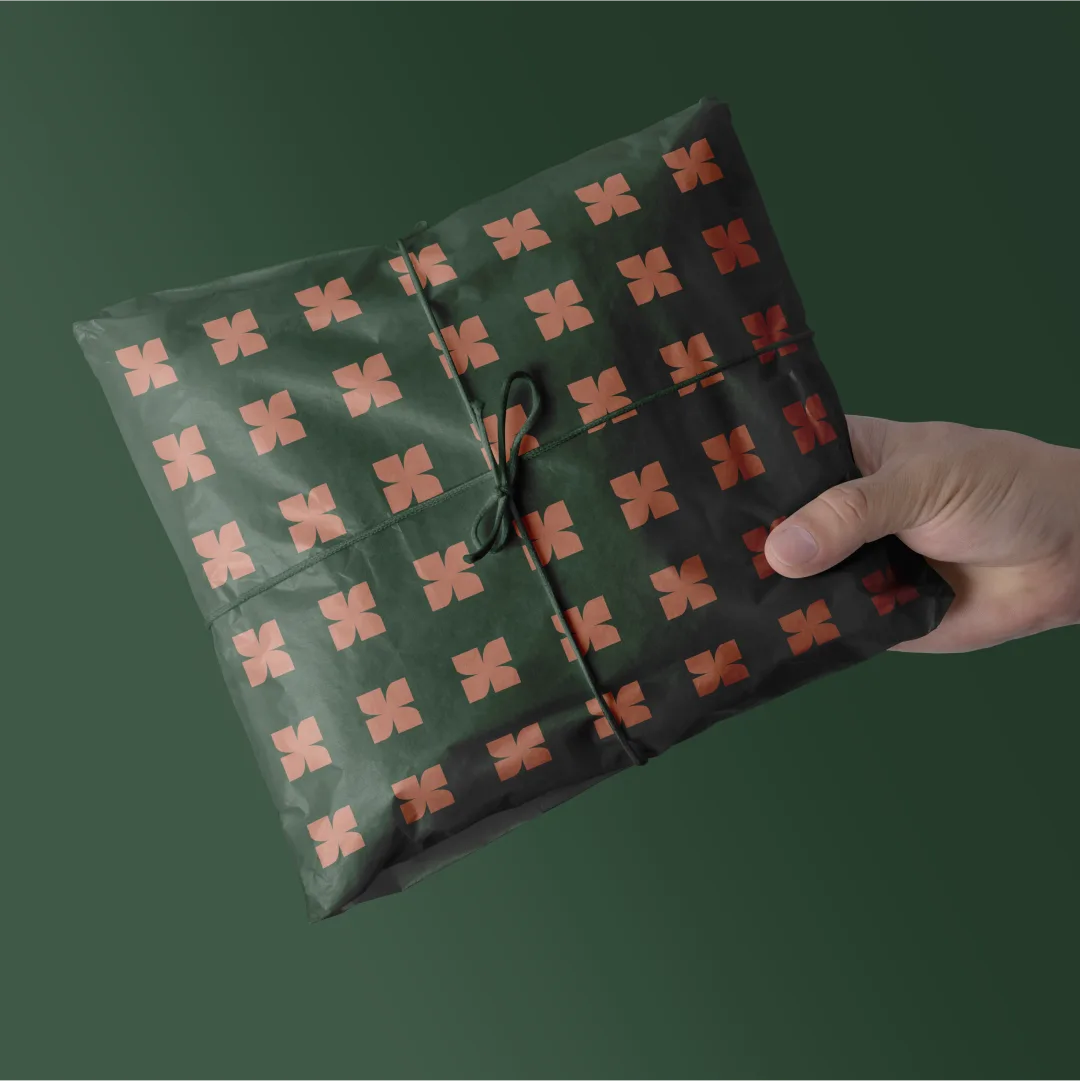 A package wrapped in Kombu Green tissue with the Soft Brown spark pattern, tied with cord