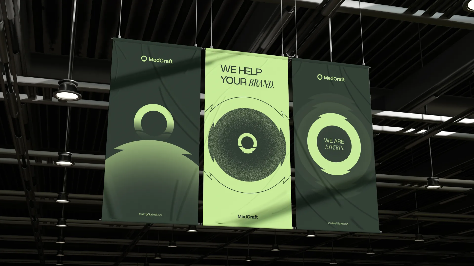 Three hanging fabric banners under warehouse lights, we help your brand and we are experts